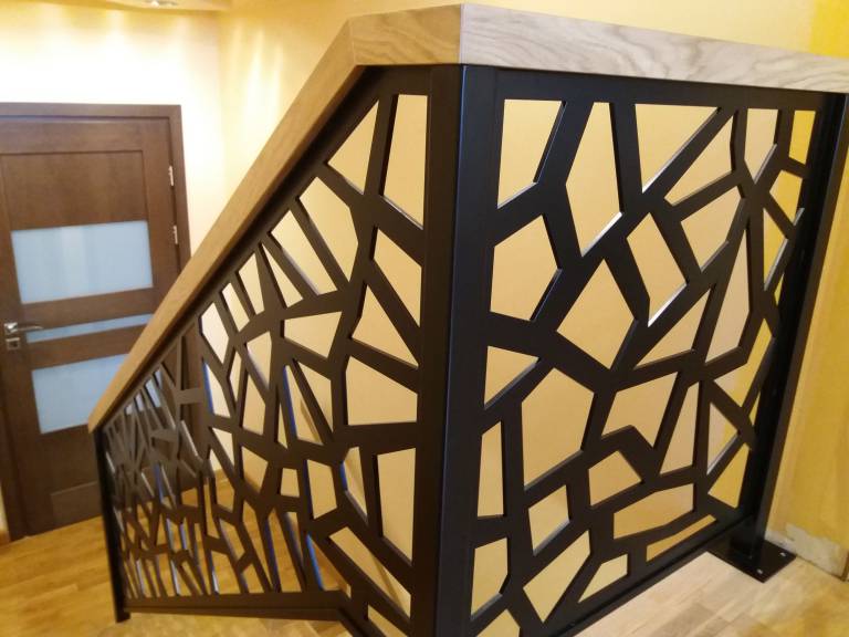 Panel ażurowy stalowy w balustradzie wewnętrznej z poręczą drewnianą.